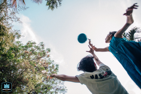 In this photo taken by a professional documentary-style family photographer, teenagers in Mexico City can be seen playing catch under the trees against a clear sky backdrop.